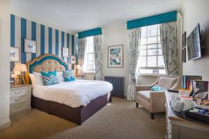 1 dormitorio con 1 cama, 1 silla y ventanas en The White Horse Hotel, Romsey, Hampshire, en Romsey