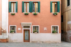 a orange building with green shuttered windows and a door at Palazzo San Luca in Venice