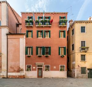 a red building with green shuttered windows and flower boxes at Palazzo San Luca in Venice