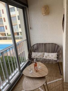 balcón con mesa, silla y ventana en Appartement T2 Gruissan port, rive gauche en Gruissan