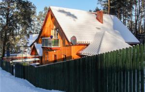 a house behind a fence with a snow covered roof at Beautiful Home In Grunwald With Wifi in Mielno