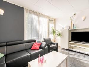 sala de estar con sofá de cuero negro y TV en Inviting holiday home in Baarland with terrace, en Baarland
