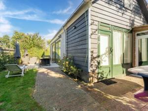 een huis met een groene deur en een bank bij Inviting holiday home in Baarland with terrace in Baarland