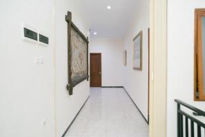 a hallway with white walls and a painting on the wall at Urbanview Hotel Griya Surya Malang by RedDoorz in Malang