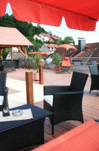 a patio with tables and chairs and a red umbrella at Gasthof und Pension Zur Frischen Quelle in Heigenbrücken