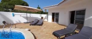 a patio with chairs and an umbrella and a pool at Casa Gemeas in Carvoeiro