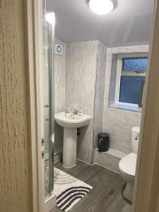 a bathroom with a sink and a toilet at Dorcas Lodge - Lovely 5 Bedroom home with free parking and Wi-Fi in Nevendon