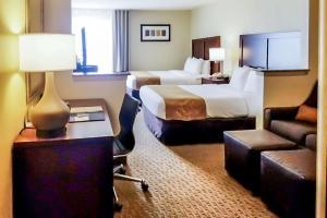 a hotel room with a bedroom with a bed and a couch at Quality Suites Las Colinas Center in Irving