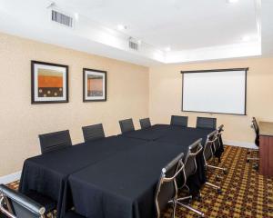 Sala de conferencias con mesa, sillas y pantalla en Quality Suites Las Colinas Center, en Irving
