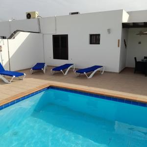 a swimming pool with two blue chairs and a table at Villa julima in Playa Blanca