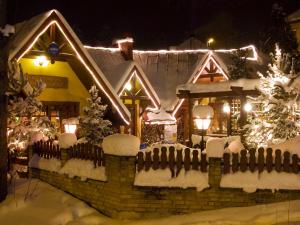 a house covered in snow at night with lights at Apartment Karkonosz in Szklarska Poręba