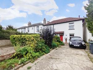 a white house with a car parked in the driveway at Dolphin Cottage - Hayling Island in South Hayling