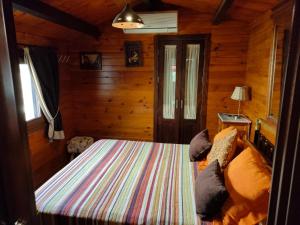 a bedroom with a bed in a wooden cabin at CABAÑA DE MADERA JUNTO AL LAGO LAS JARAS in Córdoba