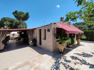 a house with a red awning on a patio at CABAÑA DE MADERA JUNTO AL LAGO LAS JARAS in Córdoba