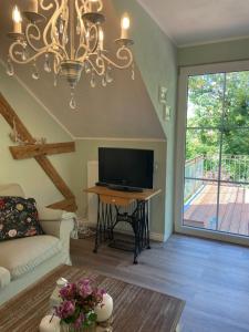 a living room with a chandelier and a tv at Neue Ferienwohnung im alten Forsthaus in Rüdesheim am Rhein