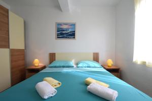 a bedroom with a blue bed with towels on it at Apartments Julia in Čižići