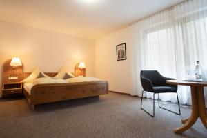 ヴァルトキルヒにあるHotel Suggenbadのベッド、テーブル、椅子が備わるホテルルームです。