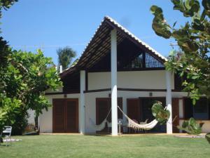 una casa con una hamaca delante en Casa Aldeia dos Pescadores - Agora com suíte e varanda no mezanino - PET Friendly, en Praia do Forte