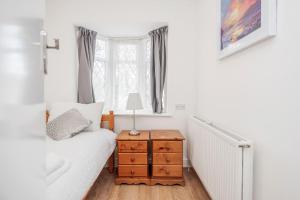 a bedroom with a bed and a table with a lamp at Lovely 4-BedRoom House Near Romford Station in Romford