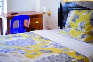a bed with a yellow and blue blanket and a desk at Kigezi Gardens Inn in Kabale