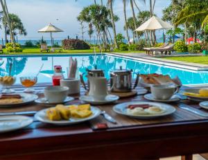 a table with plates of food next to a swimming pool at Crystal Villa in Weligama
