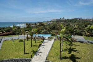 a walkway through a park with palm trees and the ocean at Premier Resort Cutty Sark in Scottburgh