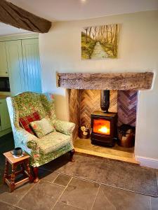 sala de estar con chimenea, silla y chimenea en Slowley Farm Cottage en Luxborough