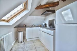 a kitchen with white cabinets and a refrigerator at Superbe appartement centre-ville in Nogent-le-Roi +8 photos