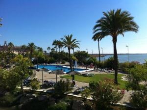 a resort with a pool and palm trees and the ocean at Moderno apartamento en Bahia Sur in San Fernando
