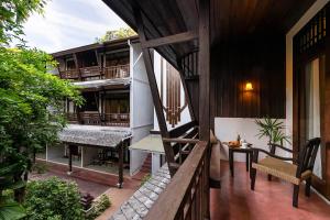 Un balcón de una casa con una mesa y un banco en Ratchapruek Lanna Boutique, en Chiang Mai