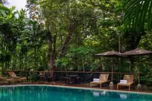 a swimming pool with chairs and an umbrella at Ratchapruek Lanna Boutique in Chiang Mai