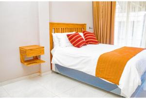 a bedroom with a bed with red and orange pillows at R Executive Apartments in Harare