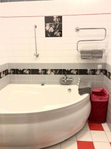 a bathroom with a white tub and a red trash can at HomeinRiga in Riga +21 photos