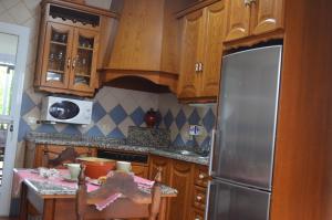 a kitchen with wooden cabinets and a stainless steel refrigerator at CASA DOROTEO in Cardeña