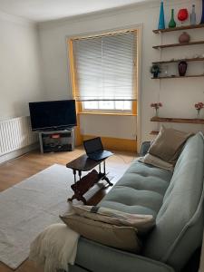 ein Wohnzimmer mit einem Sofa und einem Laptop auf dem Tisch in der Unterkunft Kensington flat with roof terrace and sunshine in London