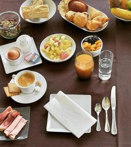 a table topped with plates of breakfast foods and drinks at Hôtel de la Marine in Saint-Herblain