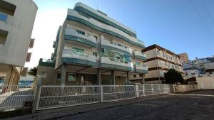 ein hohes Gebäude mit einem Zaun davor in der Unterkunft Costa do Marfim - Bombinhas in Bombinhas