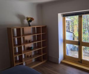 une chambre avec une étagère à côté d'une fenêtre dans l'établissement Kensington flat with roof terrace and sunshine, à Londres