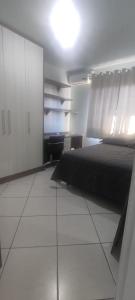 a bedroom with a black bed and white cabinets at Aconchego in Chapecó