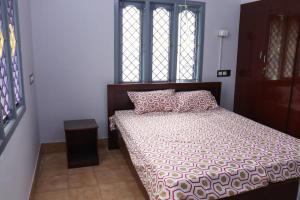 1 dormitorio con cama con almohada y ventana en Madura Homestay - Gorgeous Home with 2BHK 5 minutes from NH44, en Madurai
