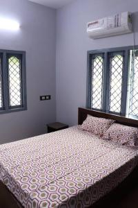 1 dormitorio con 1 cama con colcha blanca y ventanas en Madura Homestay - Gorgeous Home with 2BHK 5 minutes from NH44, en Madurai