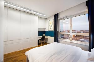 1 dormitorio con cama blanca y ventana en Qbik Artistic Cityscape Apartment, en Varsovia