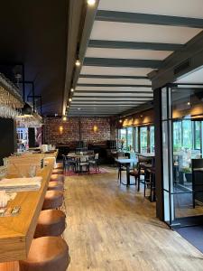 een restaurant met houten tafels, stoelen en ramen bij Hotel De Oude Molen in Groesbeek