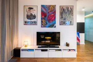 sala de estar con TV grande y carteles en la pared en Qbik Artistic Cityscape Apartment, en Varsovia