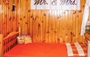 a bedroom with a wooden wall with a red bed at Nice Home In Ostrda With Kitchen in Ostróda