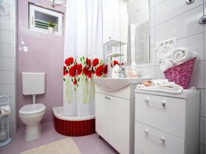 ein Bad mit einem WC, einem Waschbecken und roten Blumen in der Unterkunft Lux apartment Mare By the Sea & Beach in Baška Voda