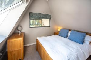 a bedroom with a bed with blue pillows and a window at Liz's Lodge by Big Skies Cottages in Weybourne