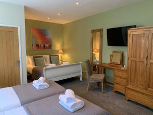 a bedroom with two beds and a desk and a television at St Agnes Hotel in St. Agnes 