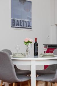 a white dining room table with chairs and a bottle of wine at Apartamenty Zatoka Górny Sopot in Sopot