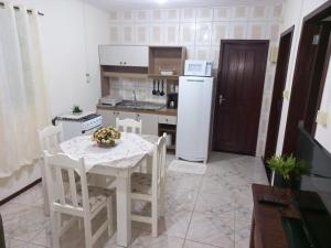a kitchen with a table and a white refrigerator at Casa inteira II - 2 quartos in Pomerode